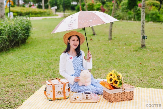 A person sitting on a blanket with an umbrella
Description automatically generated