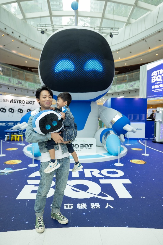 A person holding a child in front of a large robot

Description automatically generated